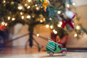 Close-up of decorations on hardwood floor against illuminated Christmas tree at home