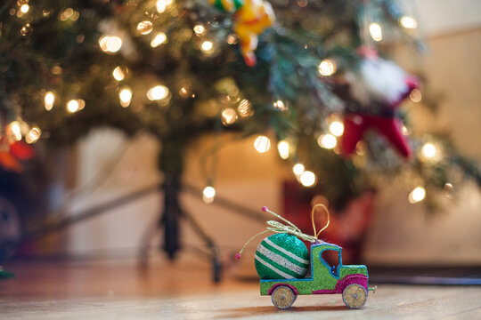 Close-up of decorations on hardwood floor against illuminated Christmas tree at home