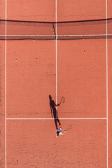 young woman playing tennis on a court with shadow hitting the ball - 579966749