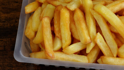 barquette de frites, en gros plan, sur une table	