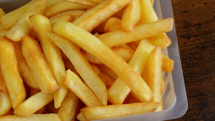 barquette de frites, en gros plan, sur une table	