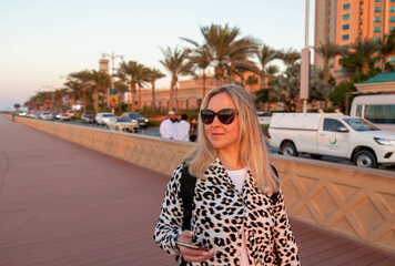 The pice capes a fashionable tourist in dark shades, relishing her trip to Dubai. Her contemporary attire exemplifies her independence and confidence, revealing her advenous spirit. 