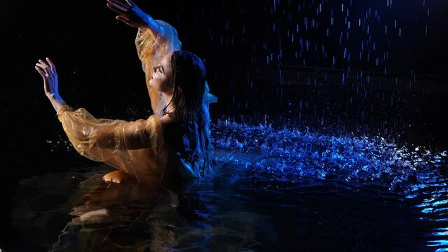 Wet beautiful woman under the falling drops of rain - photo in studio.