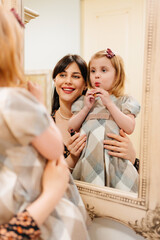 a cute little girl in a plaid dress and mom primping.