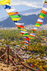 Upright landscape of Leh palace with colorful prayer flags blowing in the wind.Nepalese word on...