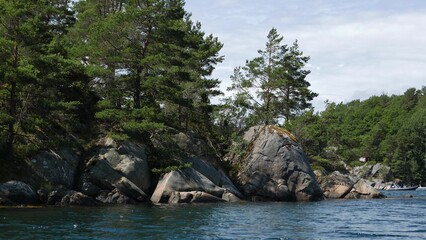 Naklejka na ściany i meble Huge boulders on the shore on a summer day.