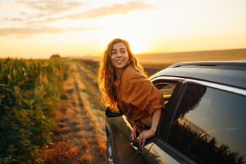 Happy woman outstretches her arms while sticking out the car window. Lifestyle, travel, tourism, nature, active life.