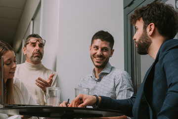 Four inter-generational group of people having fun conversation and smiling while working together on a new project at the office. Low angle view photo