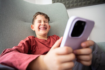 Beautiful young boy sitting on a chair with a smartphone