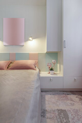 A modern bedroom in blue, pink and white colors with muffled lighting. Real photo