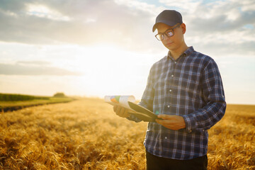 Farmer on a wheat field with a tablet in his hands. Idea of a rich harvest.