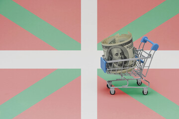 Metal shopping basket with dollar money banknote on the national flag of basque country background....