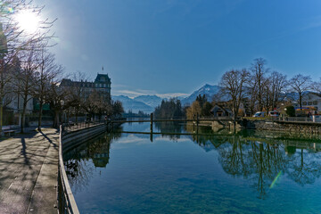 Obraz premium Scenic view of Aare River with lanterns and autumn colored trees and snow capped mountains of Swiss Alps in the background at Swiss City of Thun. Photo taken February 21st, 2023, Thun, Switzerland.