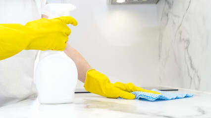 Beautiful woman in protective gloves cleaning kitchen cabinet