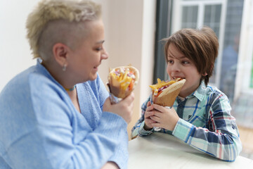 Cute little boy biting gyros in a cafe. Mother and son enjyoing their meal in a Greek fast food restaurant and having fun together