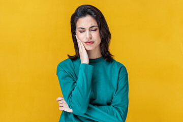 Beautiful woman with toothache touching her face on isolated on yellow