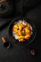 Portion of asian spicy honey shrimp with rice on black background