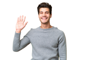 Young handsome caucasian man over isolated background saluting with hand with happy expression