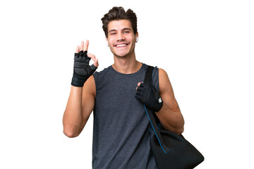 Young sport caucasian man with sport bag over over isolated background showing ok sign with fingers