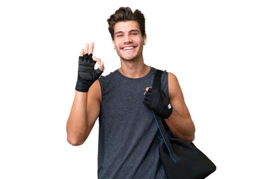 Young sport caucasian man with sport bag over over isolated background showing ok sign with fingers