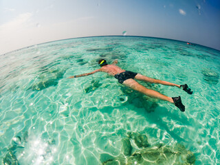 man snorkeling in crystal clear tropical sea