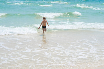 Fototapeta na wymiar happy boy running on the waves of the sea 