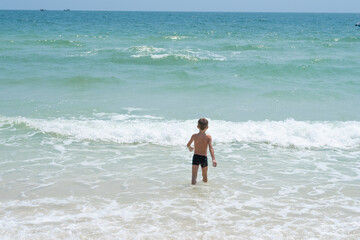 Fototapeta na wymiar happy boy running on the waves of the sea