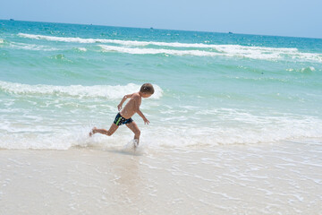 Fototapeta premium happy boy running on the waves of the sea 
