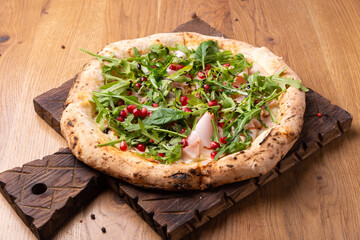 Oven-cooked Italian pizza Melagrano with Mozzarella cheese, ham, beef, arugula, pomegranate seeds, basil and olive oil.