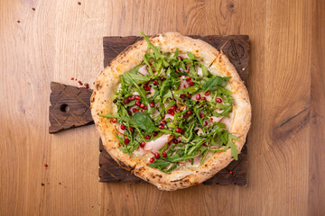 Oven-cooked Italian pizza Melagrano with Mozzarella cheese, ham, beef, arugula, pomegranate seeds, basil and olive oil.