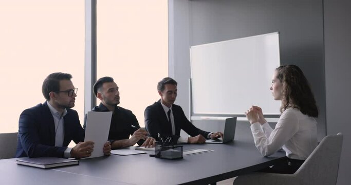 Young female applicant pass job interview in company office with three male HR managers ask questions listen answers of confident woman position candidate. Formal meeting in boardroom, human resources