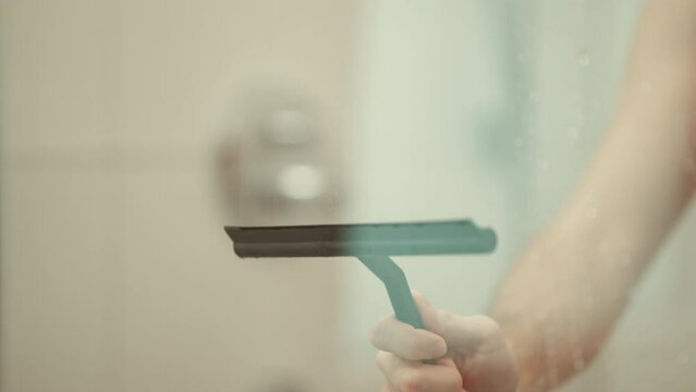 Man cleaning the shower glass after taking a shower.