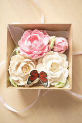 sweet dessert, gift, marshmallow peony flowers in a package, on a light background. Sugar addiction, consumption, handmade dessert. Low-calorie marshmallow, carbohydrates, decorative butterfly