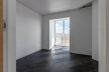 Empty apartment with large floor-to-floor window overlooking nature and blue sky with clouds