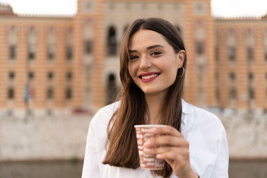 The smiling young woman drinks coffee to Go
