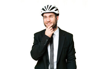 Business person with a bike helmet over isolated chroma key background thinking an idea while looking up