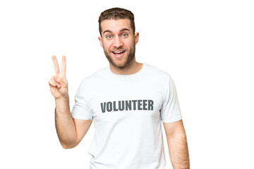 Naklejka premium Young volunteer man over isolated chroma key background smiling and showing victory sign
