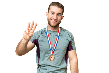 Young handsome blonde man with medals over isolated chroma key background happy and counting three with fingers
