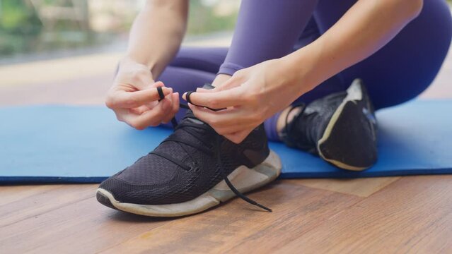 Close up of woman athlete do tying shoe laces. 4k Slow motion. Active lifestyle concept. Young sporty lady athlete wearing sportswear tying shoelaces on her sneakers. Footage b roll.