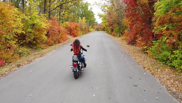 Young Woman With Long Hair Rides A Motorcycle On An Autumn Forest Road