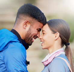 Fototapeta premium Man, woman and forehead touch for hiking, love and happiness in nature for outdoor adventure on holiday. Young happy couple, training and smile with care, bonding and vacation in countryside together