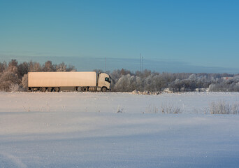 A big white truck drives down the highway on a cold winter morning