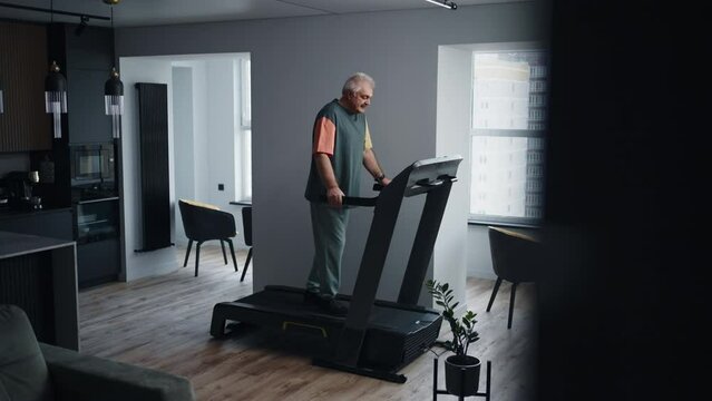 Mature Man Using Treadmill For Saving Health And Keeping Fit, Training Alone At Home