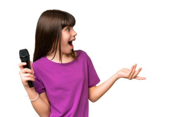 Little singer girl picking up a microphone over isolated background with surprise facial expression