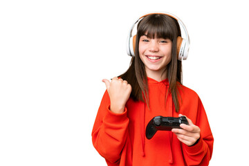 Little caucasian girl playing with a video game controller over isolated background pointing to the...