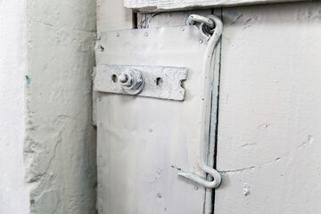 Old wooden door painted white with a latch instead lock.