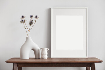 Empty vertical frame mockup in modern minimalist interior with plants on white wall background,...