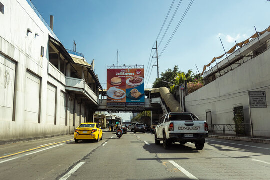 Makati, Metro Manila, Philippines - March 2023: Northbound lane of EDSA with the MRT-3 Buendia station above. A poster of Jollibee hands on a elevated walkway.