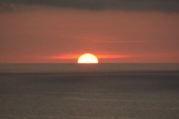 Fototapeta na wymiar sol poniéndose en el horizonte del mar