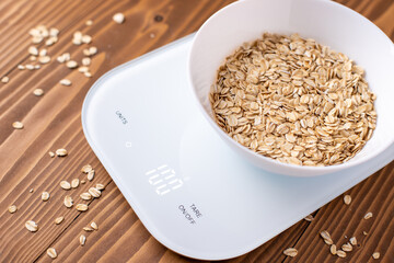 Oatmeal in a white bowl on the kitchen scales